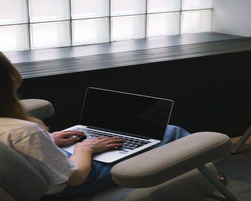 Person typing on a laptop with an ergonomic posture and comfortable chair